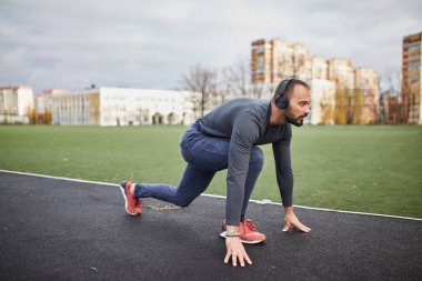 Atlet stadyumda çalışır. Kulaklıklar ile genç bir adam. atlet başlayan blok üzerinde