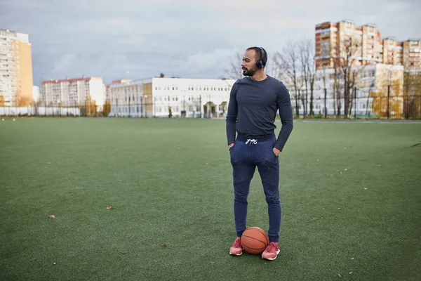 Stadyumda basketbol ile sporcu. Genç adam bir basketbol topu ile kulaklık — Stok fotoğraf