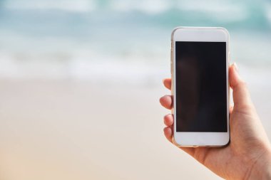 Hareket eden telefon içinde plaj ve okyanus zemin üzerine el