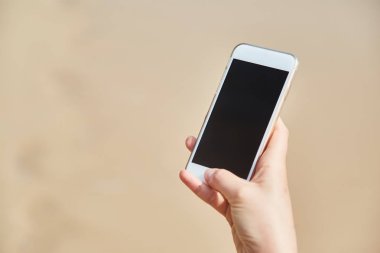 Hareket eden telefon içinde plaj ve okyanus zemin üzerine el