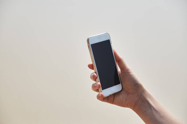 Mobile phone in female hand on the background of the beach and ocean