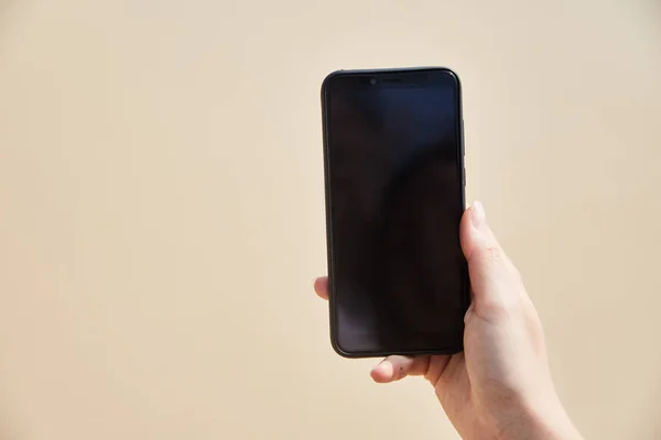 Mobile phone in female hand on the background of the beach and ocean — Stock Photo, Image