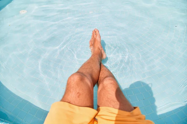 Feet dipped in swimming pool water