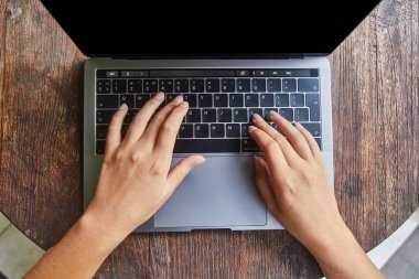 Boş akıllı telefon ile ahşap ofis masaüstünde yerleştirilen dizüstü tuş takımı yazarak güzel kadın elleri üst görünümü.