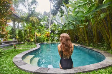 Genç bir kız havuzda yüzüyor.