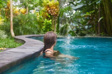 Genç bir kız havuzda yüzüyor.