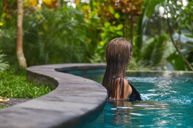 Genç bir kız havuzda yüzüyor.