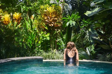 Genç bir kız havuzda yüzüyor.