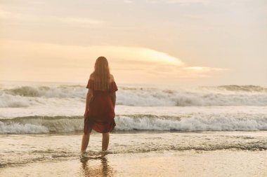 Güzel gün batımı. Okyanus sahilinde yürüyen genç kadının silueti.