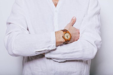 Elinde saat olan zarif beyaz gömlekli bir adam.