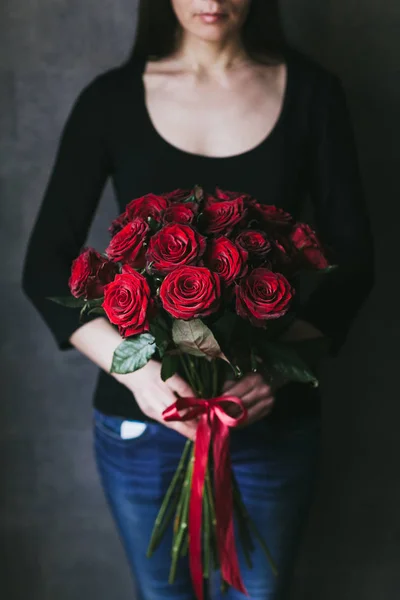 Ramo de rosas rojas en las manos de una mujer — Foto de Stock