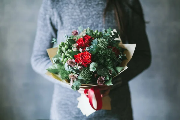 Un ramo de flores rojas en las manos de una mujer — Foto de Stock