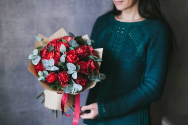 Bir kadının elinde kırmızı çiçek bir buket