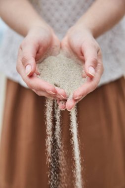 Girl pouring sand out of her hands. clipart
