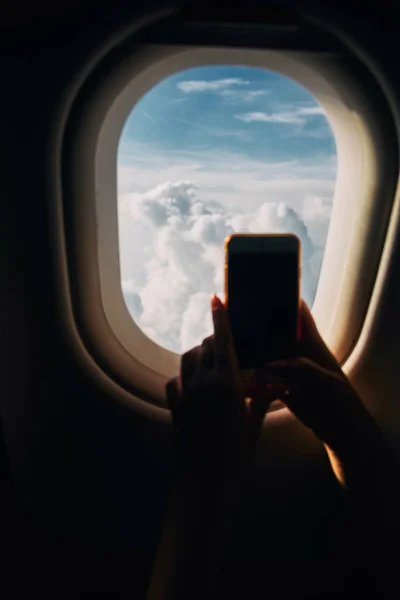 Jovem mulher fotografando vista da janela da aeronave durante o voo no avião — Fotografia de Stock