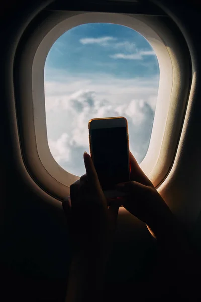 Jovem mulher fotografando vista da janela da aeronave durante o voo no avião — Fotografia de Stock