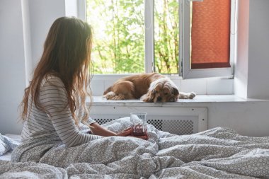 Genç kız yatakta çay içiyor