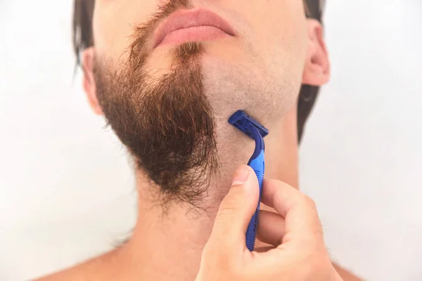 Meio barbeado. Um jovem com barba na metade do rosto em fundo cinza claro . — Fotografia de Stock