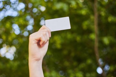 Alışveriş için elinde beyaz bir kredi kartı tutan kız. 