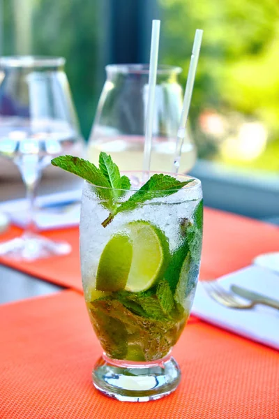 Mojito cocktail with lime and mint in a glass on the table in a sunny day — Stock Photo, Image