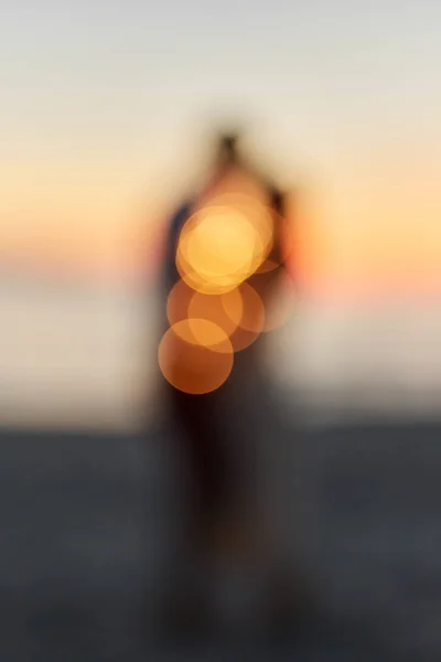 一对年轻夫妇在日落时在海边接吻的剪影。模糊背景. — 图库照片