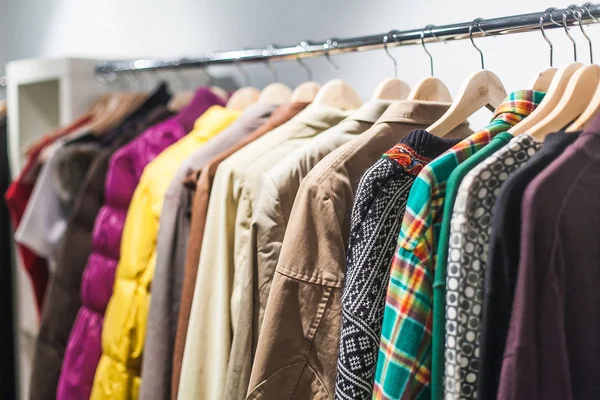 Seleção colorida de roupas para homens e mulheres pendurados em cabides em um shopping para um conceito de venda de loja . — Fotografia de Stock