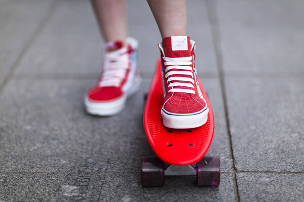 Girl in red sneakers put her foot on a skateboard