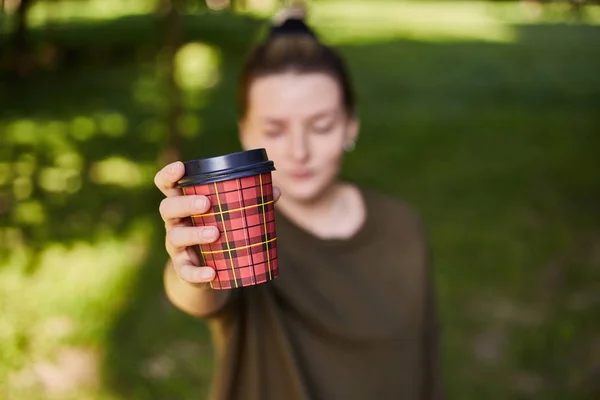 Jeune fille tient un verre avec du café au premier plan . — Photo