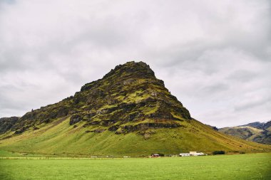 İzlanda'daki volkanik dağlar. Dağlara yakın tarlada çiftlik. 