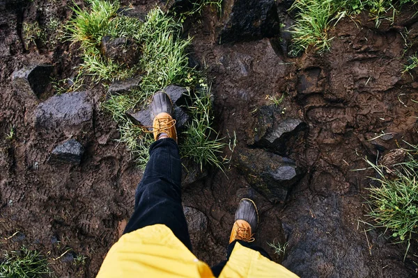 Młody mężczyzna stoi na kamieniach w gumowych butach. Islandia — Zdjęcie stockowe