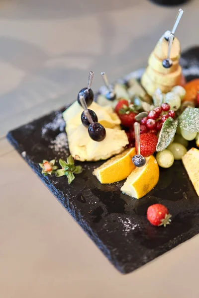 Fruta cortada en rodajas en un plato elegante. Piña, pera, naranja, manzana, uva, fresa silvestre . —  Fotos de Stock