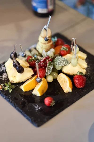 Fruta cortada en rodajas en un plato elegante. Piña, pera, naranja, manzana, uva, fresa silvestre . —  Fotos de Stock