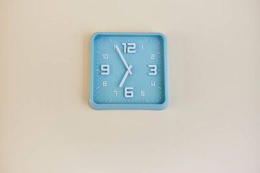 beyaz bir duvarda asılı turkuaz saat