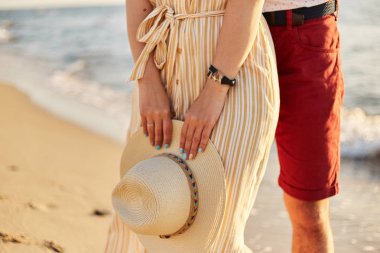 Bir kızın elinde hasır bir şapka. Sahil boyunca yürüyün