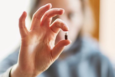 Genç bir kız elinde bir tablet tutar. Elinde kapsül. Ilaç. İlaç