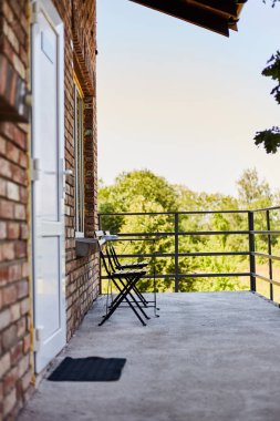Rahatlamak için bir yer. Bir kır evinin terası. Sandalyeli masa.