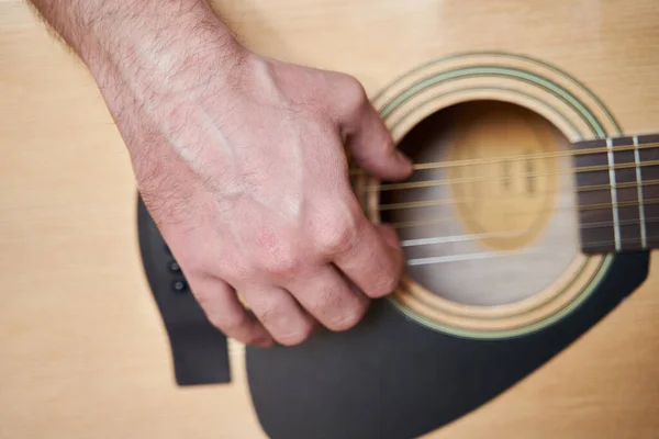 Guitar Player Hand or Musician Hand on Acoustic Guitar String with soft natural light in close up view