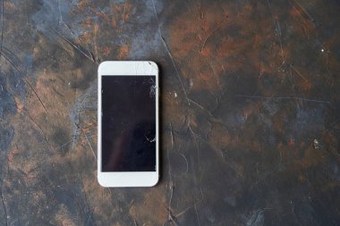 Siyah arka planda kırık ekranlı beyaz telefon