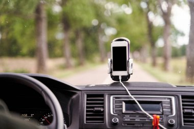 Arabada GPS kartı olan cep telefonu. Arabada duran beyaz bir akıllı telefon navigasyon için kullanılır..