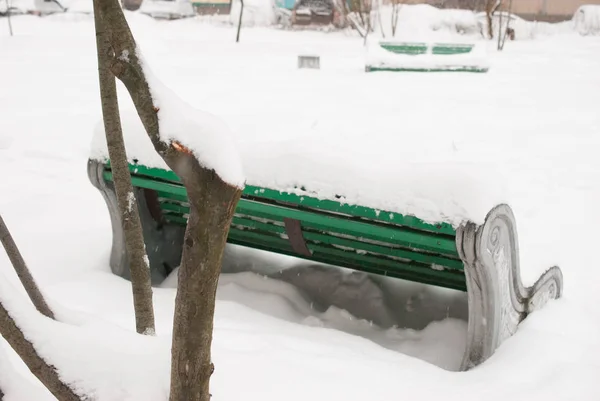 stairs and bench covered with snow. the drifts and snow piles