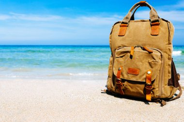 seyahat, tatil. Denizin kenarında kumlu bir plajı olan boş tropikal bir yer. Sahilde bir gezginin sırt çantası. Mavi gökyüzü ve arka planda çürük deniz. Yapıştırılacak yer, kopyalama yeri
