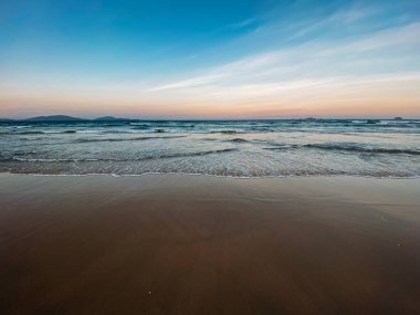 Deniz manzaralı. Denizde dalgalar, gelgit, kumlu sahil, köpük. Mavi gökyüzünde güzel bulutlar. Asya 'da seyahat. Denizde gün batımı, renkli gökyüzü. Yer kopyala