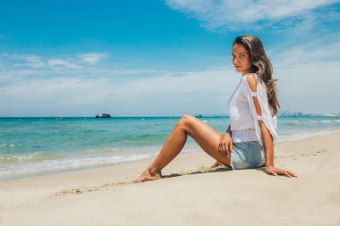 Genç ve güzel bir kız, çürük suyu ve mavi gökyüzü ile beyaz kumlu bir plajda, tatil sırasında, tropik bir tatil beldesine yolculuk yapıyor. Deniz manzarası, yaz tatili ve seyahat konsepti