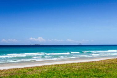Güzel bir arka plan ya da ekran koruyucu için tropikal egzotik bir plaj manzarası, denizde masmavi su ve beyaz bulutlu açık mavi gökyüzü. Seyahat konsepti, yaz tatili. Yer kopyala