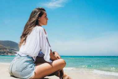 Deniz kıyısında genç bir kız, arkadan manzaralı. Denize doğru bakıyor, düşünüyor. Meditasyon. Deniz Burnu