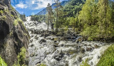 Panorama ve derin bir vadi ile güzel ve görkemli doku Dağları bir sahne ve bir dağ nehir mavi gökyüzü bulutlu karşı bir acele akışı. Altay, Sibirya, Rusya Federasyonu. Şelale Uchar.