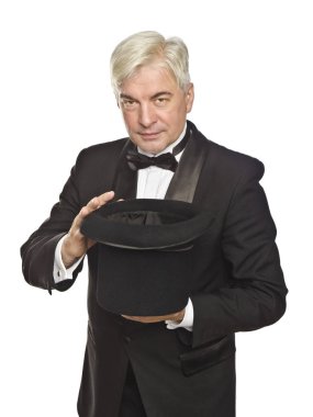 Elinde siyah bir şapka ile siyah bir smokin yaşlı bir gri saçlı prestidigitator büyü hileci beyaz bir arka plan üzerinde gösterir.