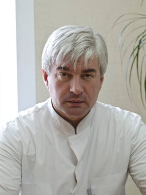 Beyaz önlük Agrey saçlı erkek doktor. Agrey saçlı erkek doktor hastaya kapalı arıyorsunuz bir Beyaz laboratuar coatattentively içinde.