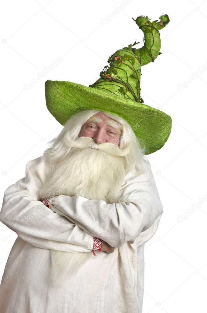 Cunning funny magician in a green cap with a long gray beard on a white isolated background