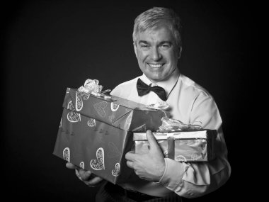 Hediyeler ile saygın adam heybetli bir gri saç kırmızı. Veren yakışıklı heybetli saygın bir gri saç ed adam kırmızı kaydırma paperagainst siyah bir arka plan sunuyor..